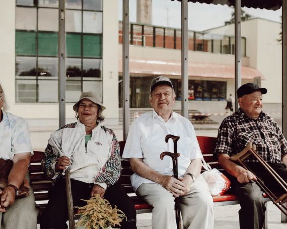 Group of seniors sitting together on a bench, enjoying a relaxed moment in an urban setting.